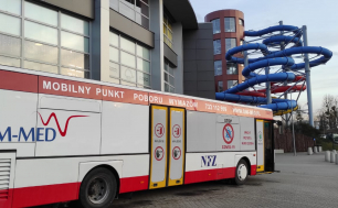 Zdjęcie przedstawia autobus (Mobilny Punkt Poboru Wymazów) stojący pod Parkiem Wodnym "Trzy Fale"