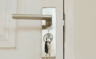 Na zdjęciu widzimy jasne drzwi z pękiem kluczy w zamku