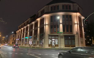 Zdjęcie poglądowe ukazujące ulicę Anny Łajming i nieruchomości przy drodze, jak Złota Kamienica. Na jezdni auta, zdjęcie nocne, lampy i światła w tle