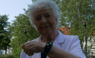 Zdjęcie przedstawia seniorkę z opaską SOS na ręku.