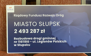 na zdjęciu widzimy symboliczny czek z napisem Rządowy Fundusz Rzwoju Dróg Miasto Słupsk 2 493 287 zł Rozbudowa drogi gminnej nr 116 118 G- ul. Legionów Polskich w Słupsku