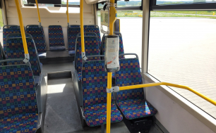 Na zdjęciu widzimy wnętrze autobusu miejskiego- siedzenia i uchwyty oraz  nowy element Systemu Fali - zafolionwany holder