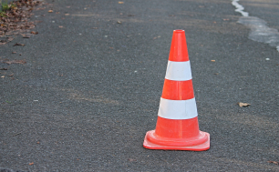 jezdnia asfaltowa a na niej stojący pomarańczowo-biały pachołek ostrzegawczy; Image by Manfred Richter from Pixabay