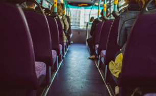 Na zdjęciu widzimy wnętrze autobusu miejskiego- siedzenia i uchwyty oraz  ramiona pasażerów