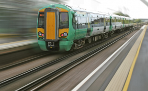 Na zdjęciu widizmy pociąg  w barwach zieleni i pomarańczy . Obraz sprawia wrażenie szybko jadącego składu.