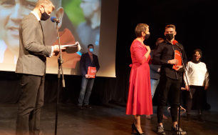 Na zdjęciu widzimy sześć osób na scenie Teatru RONDO -Panią Prezydent w czerwonej sukience na pierwszym planie oraz nagradzonego sportowca jak również Pełnomocnika Prezydenta ds. Sportu