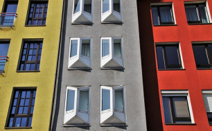Zdjęcie przedstawia  kolorowy  wysoki budynek mieszkalny