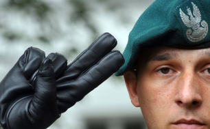 Na zdjęciu widzimy twarz i dłoń salutującego żołnierza
