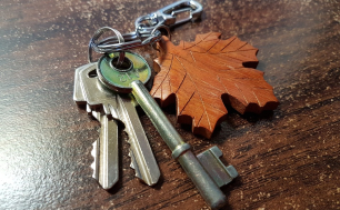 Na zdjęciu widzimy pęk kluczy do drzwi z drewnianym brylokiem w kształcie liścia
