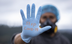 zdjęcie przedstawia dłoń w niebieskiej rękawiczce na której widnieje napis STOP COVID-19 (fot. pixabay)