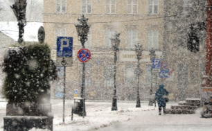Widok na pl. Zwycięstwa i chodnik przy ratuszu, lampy, znaki drogowe, schody do ratusza i bardzo dużo śniegu i sypiący opad