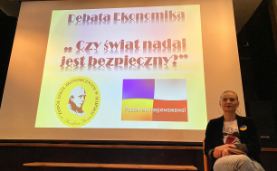 Na zdjęciu widzimy Wiceprezydentkę Martę Makuch, siedzącą na krześle przed ekranem z napisem Debata Ekonmika - Czy świat nadal jest bezpieczny?